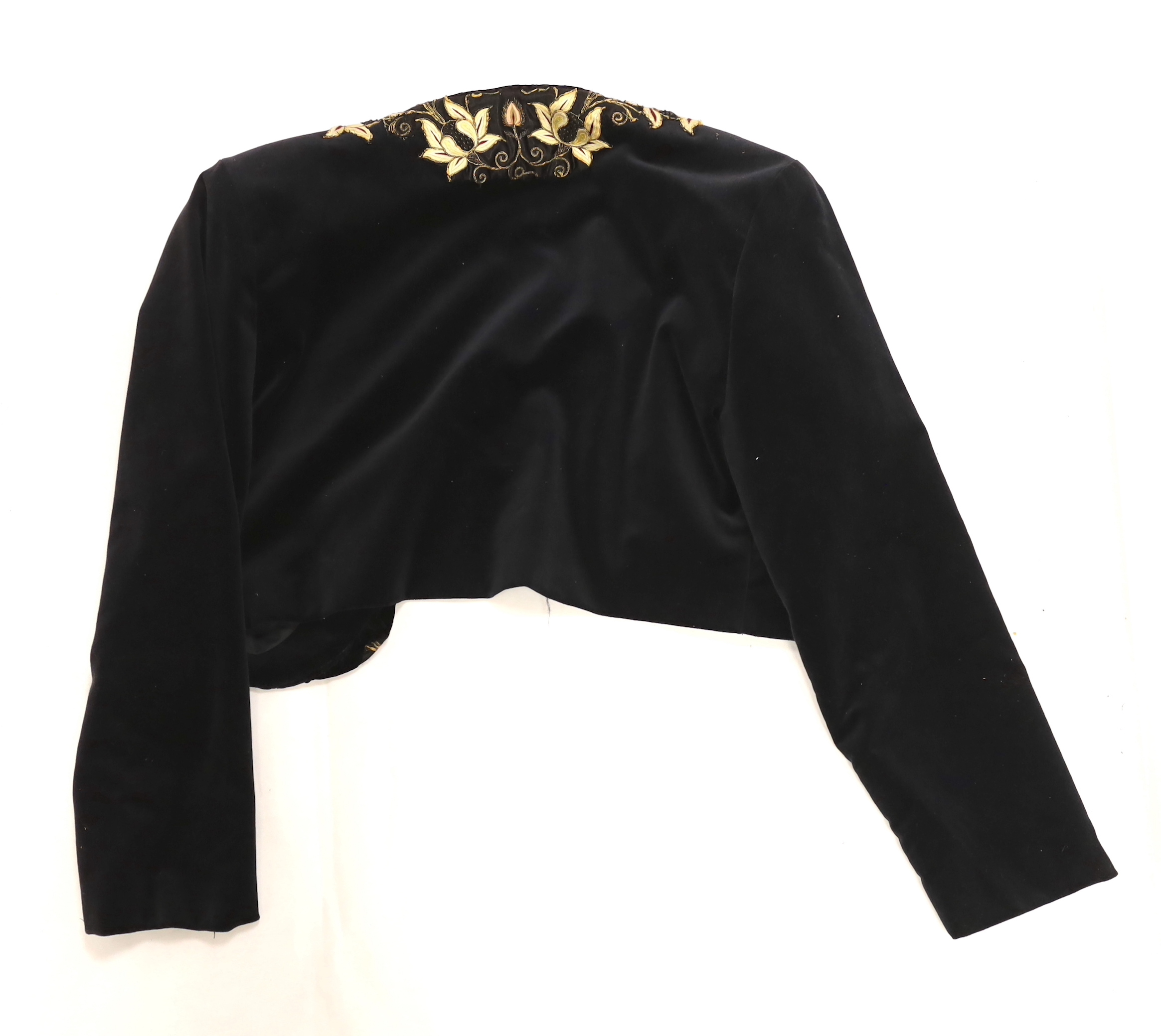A velvet bolero with ornate polychrome silk embroidered and beaded panels, together with a full length black tape lace evening skirt (some damage) with red satin waisted sash